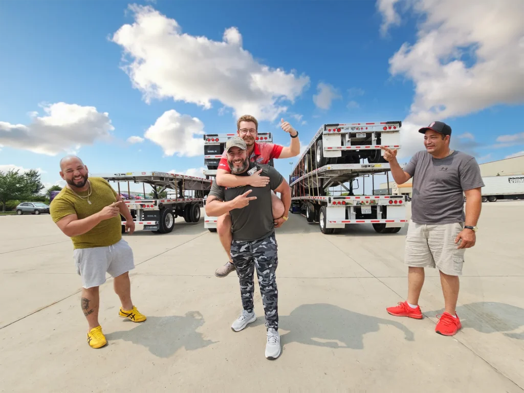 Truckers in front of stacks of used Semi Flatbed Trailers