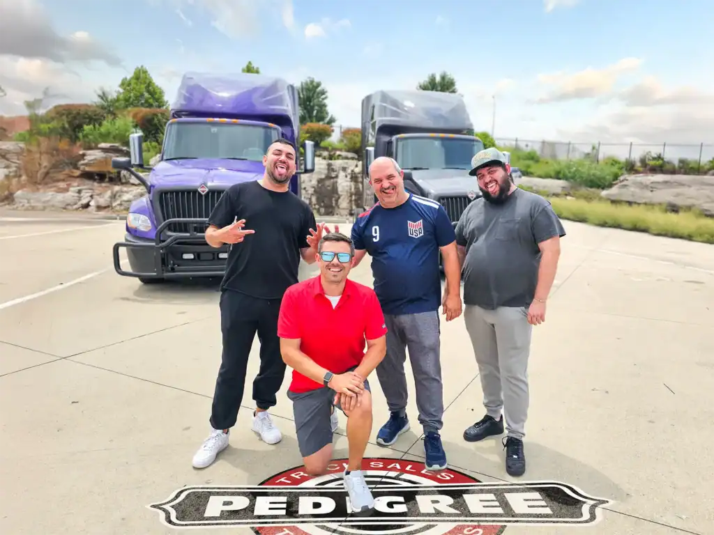 Truckers posing in front of a two used LT625 International Semi Trucks that came with a free warranty